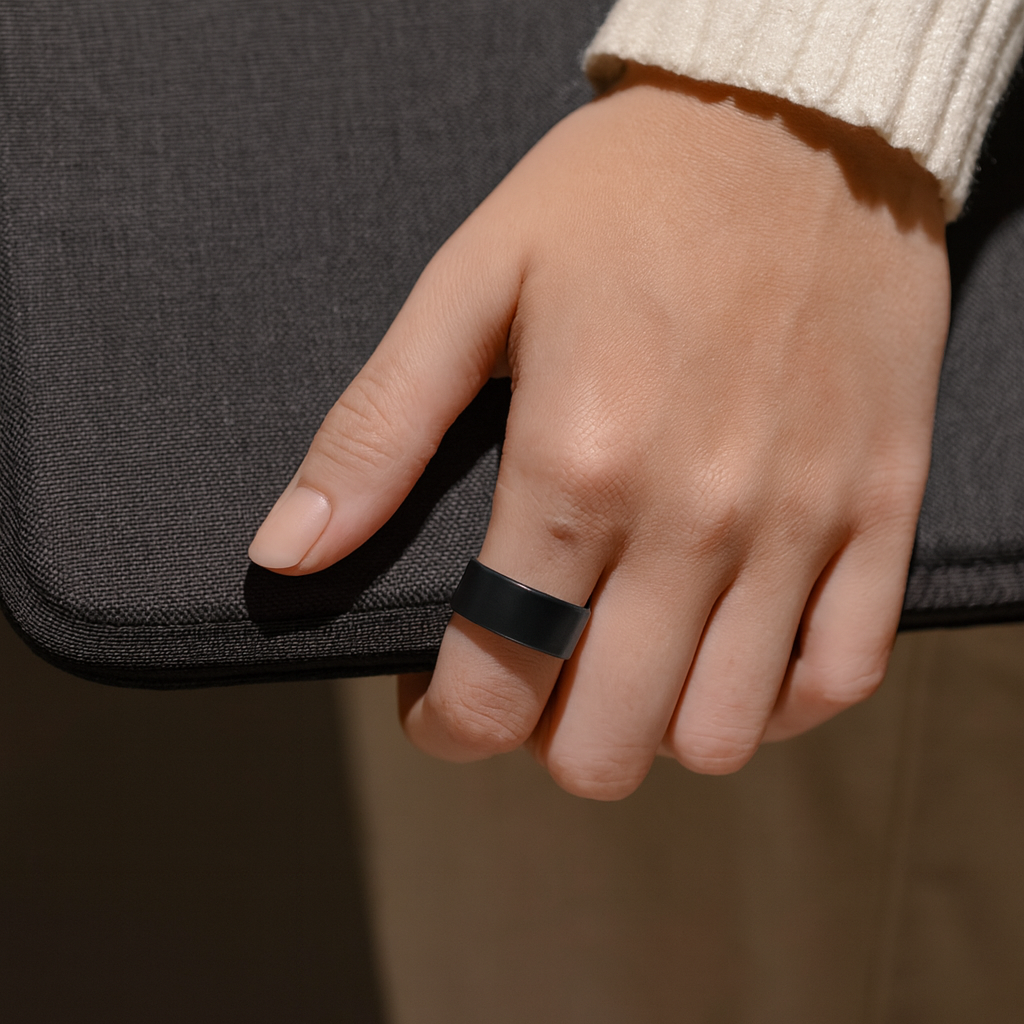 Hand wearing a black ring on a dark background
