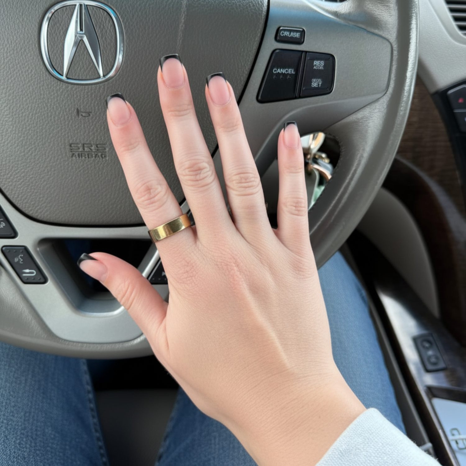 Hand with a gold ring on an Acura steering wheel