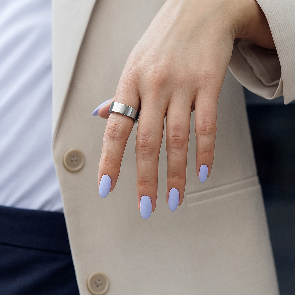 Hand with light purple nail polish wearing a silver ring, against a neutral background.